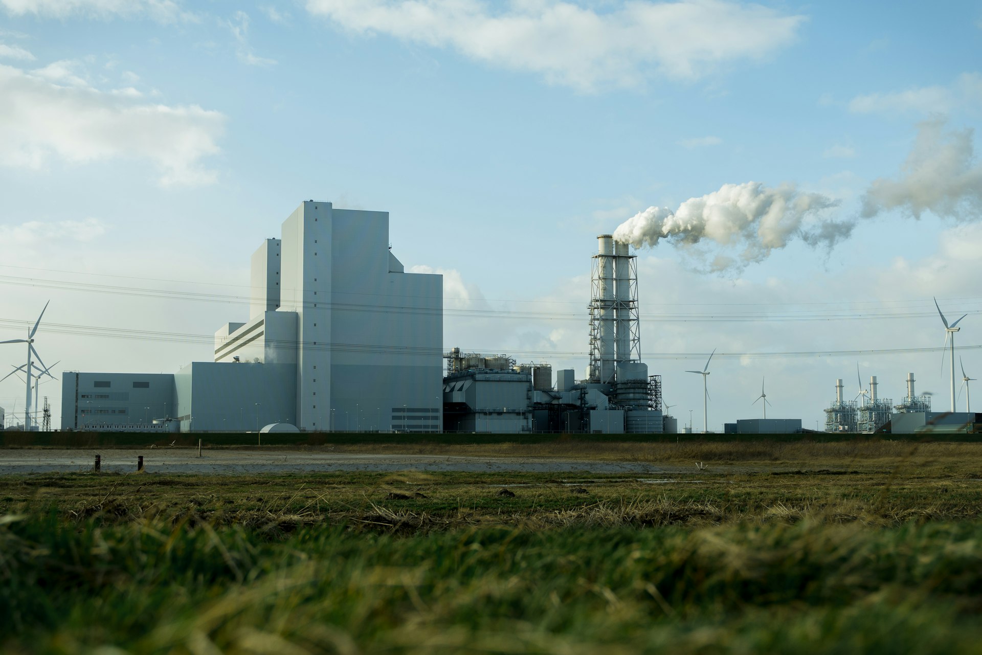 white and gray factory under white clouds during daytime